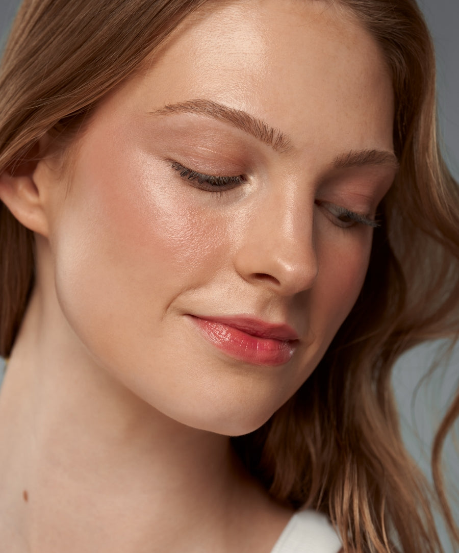 Close-up of a woman with natural, glowing skin and soft makeup showcasing the radiant finish of the ReDimension Daily Glow Palette, highlighting clean beauty and natural ingredients.