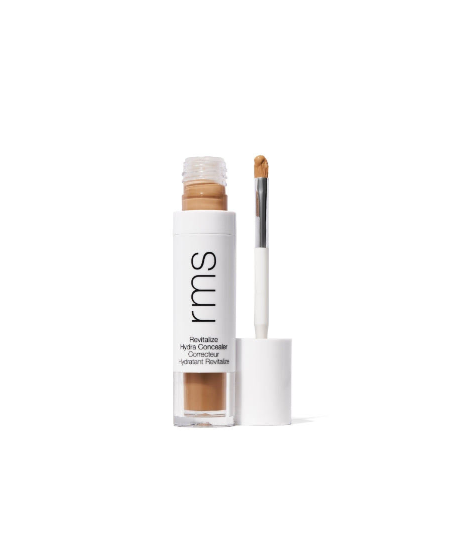 Revitalize Hydra Concealer in a sleek white tube beside an applicator wand with a medium beige shade, showcasing clean beauty and skincare infused makeup qualities.