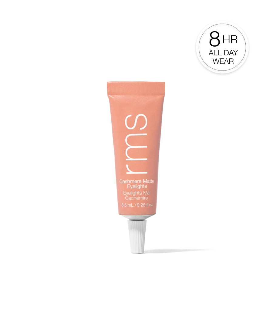 Tube of Cashmere Matte Eyelights in a soft peach shade standing upright with simple white text branding and a badge indicating 8-hour all-day wear, promoting clean beauty and sustainable packaging.