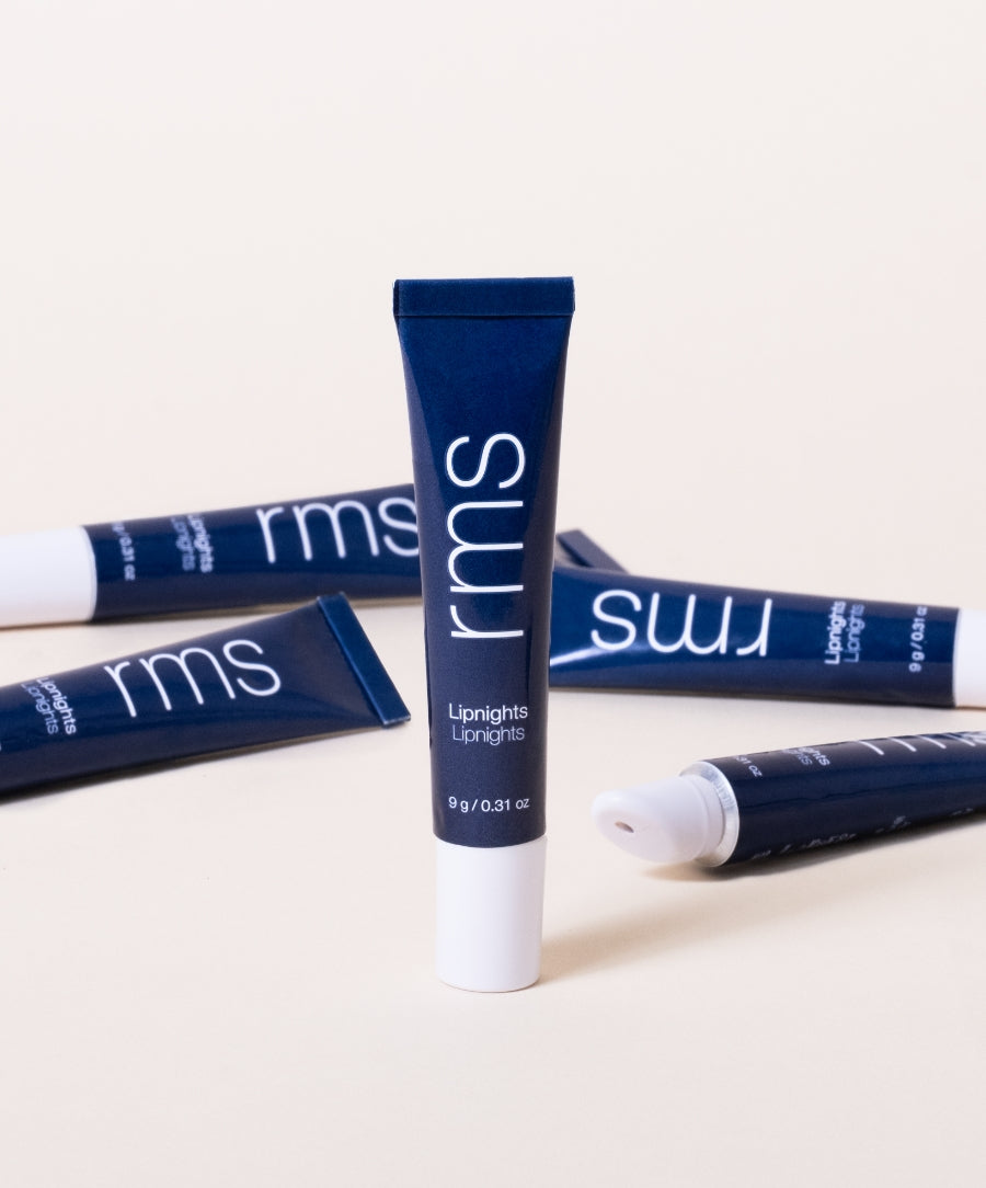 Tube of Lipnights Overnight Lip Mask in sleek navy blue packaging with white text, arranged on a light background showcasing clean beauty and natural ingredients.