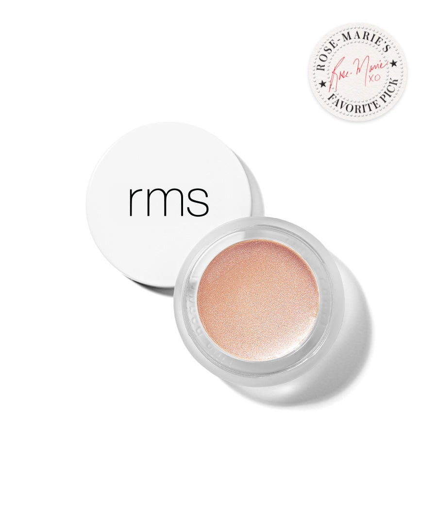 Open container of Luminizer with a soft champagne rose cream highlighter in a white jar featuring minimalist black lettering, showcasing a clean beauty makeup product.