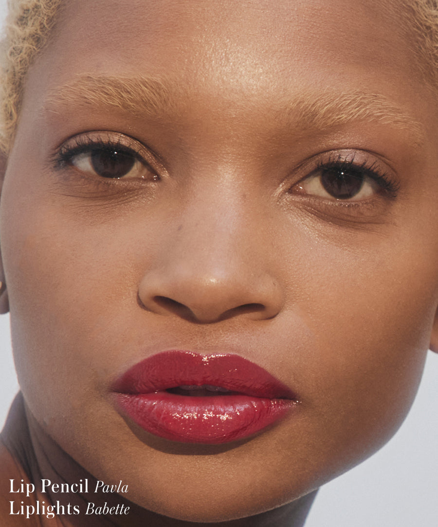 Close-up of a person wearing glossy deep red Liplights Cream Lip Gloss with natural skin and minimal eye makeup, showcasing a clean beauty look.