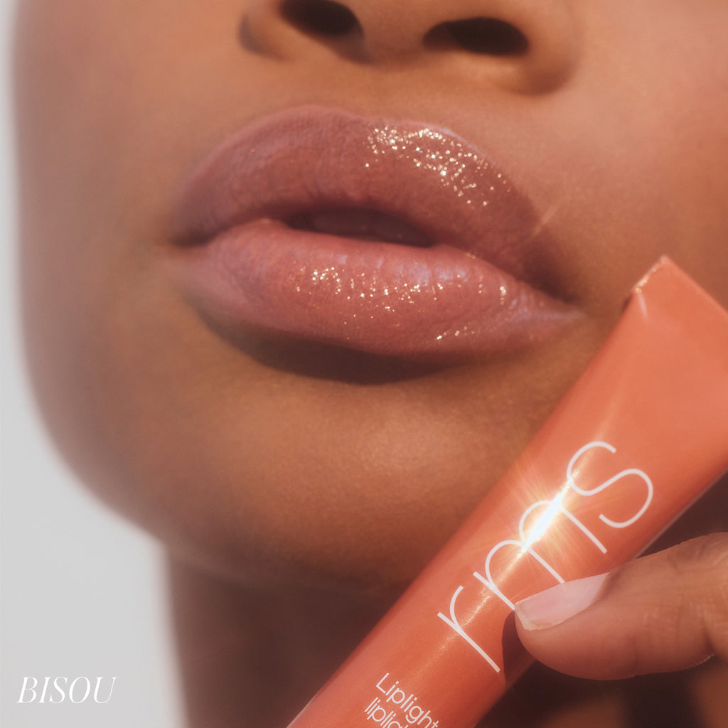 Close-up of glossy lips wearing Liplights Cream Lip Gloss with natural, radiant shine, held alongside the sleek orange tube of the product, highlighting clean beauty and natural ingredients.