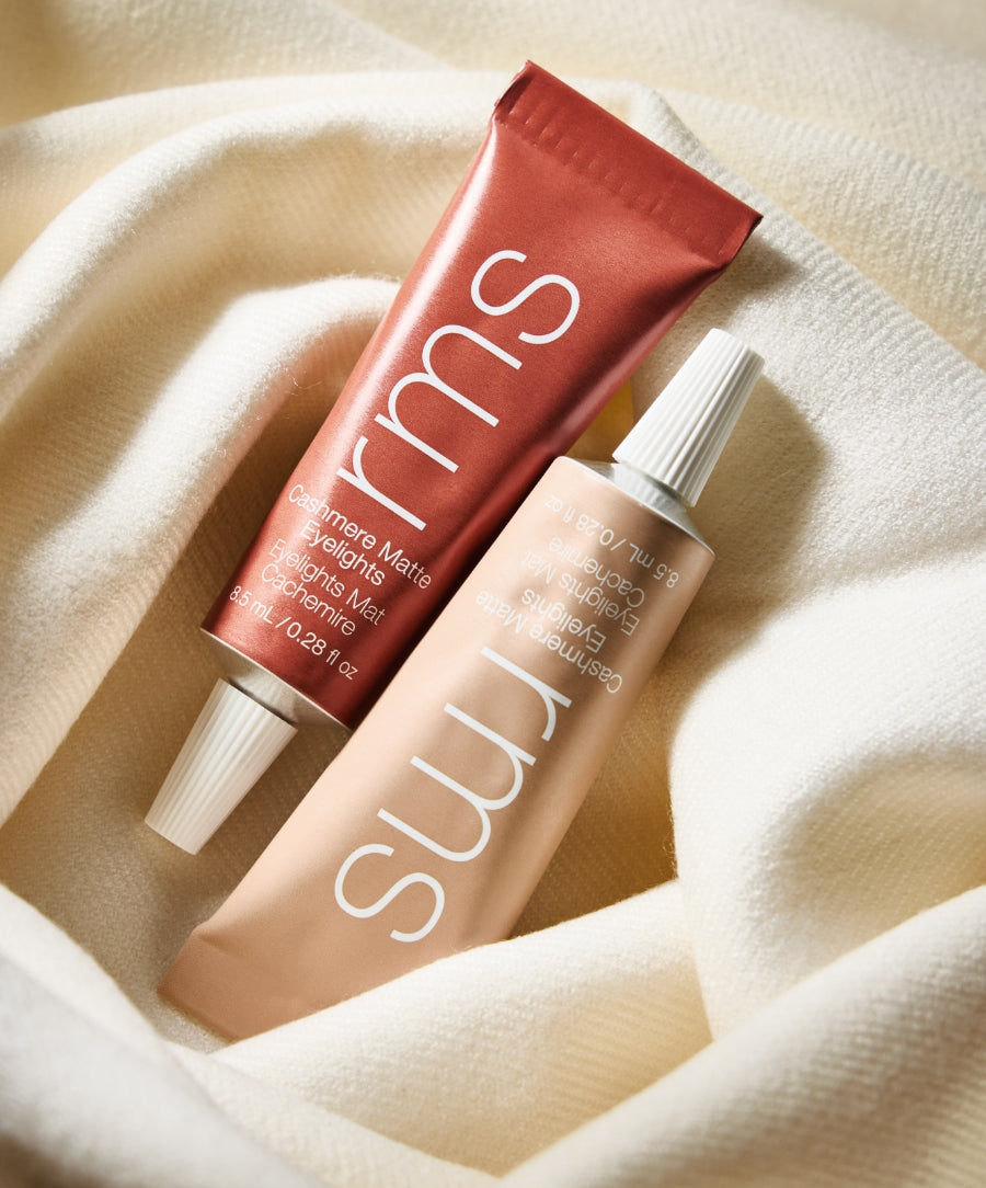 Two tubes of Cashmere Matte Eyelights makeup resting on a soft cream-colored fabric, highlighting clean beauty and natural ingredients.