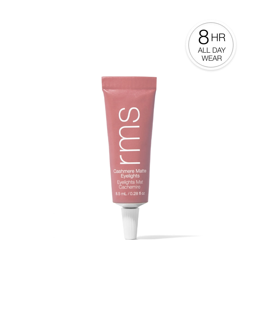 Tube of Cashmere Matte Eyelights makeup in soft pink shade standing upright with 8-hour all day wear badge, highlighting clean beauty and natural ingredients by RMS Beauty.