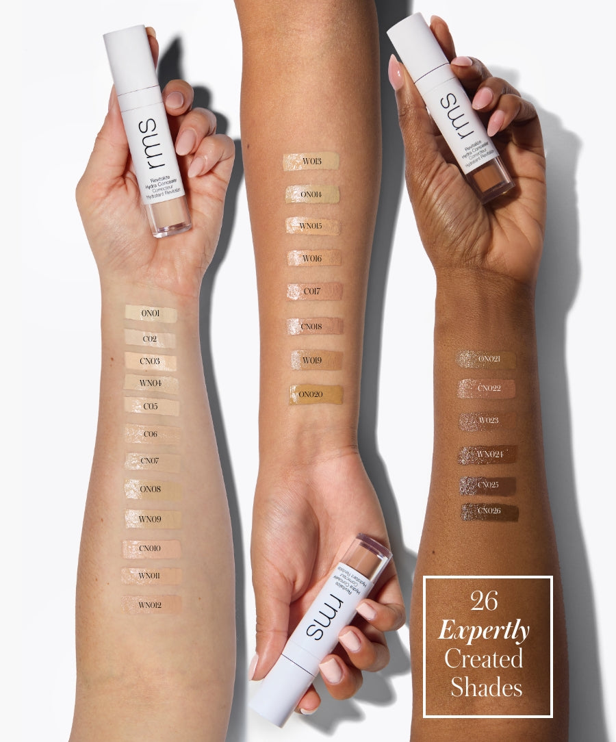Three arms of different skin tones display multiple swatches of Revitalize Hydra Concealer in 26 expertly created shades, each arm holding a tube of the product.