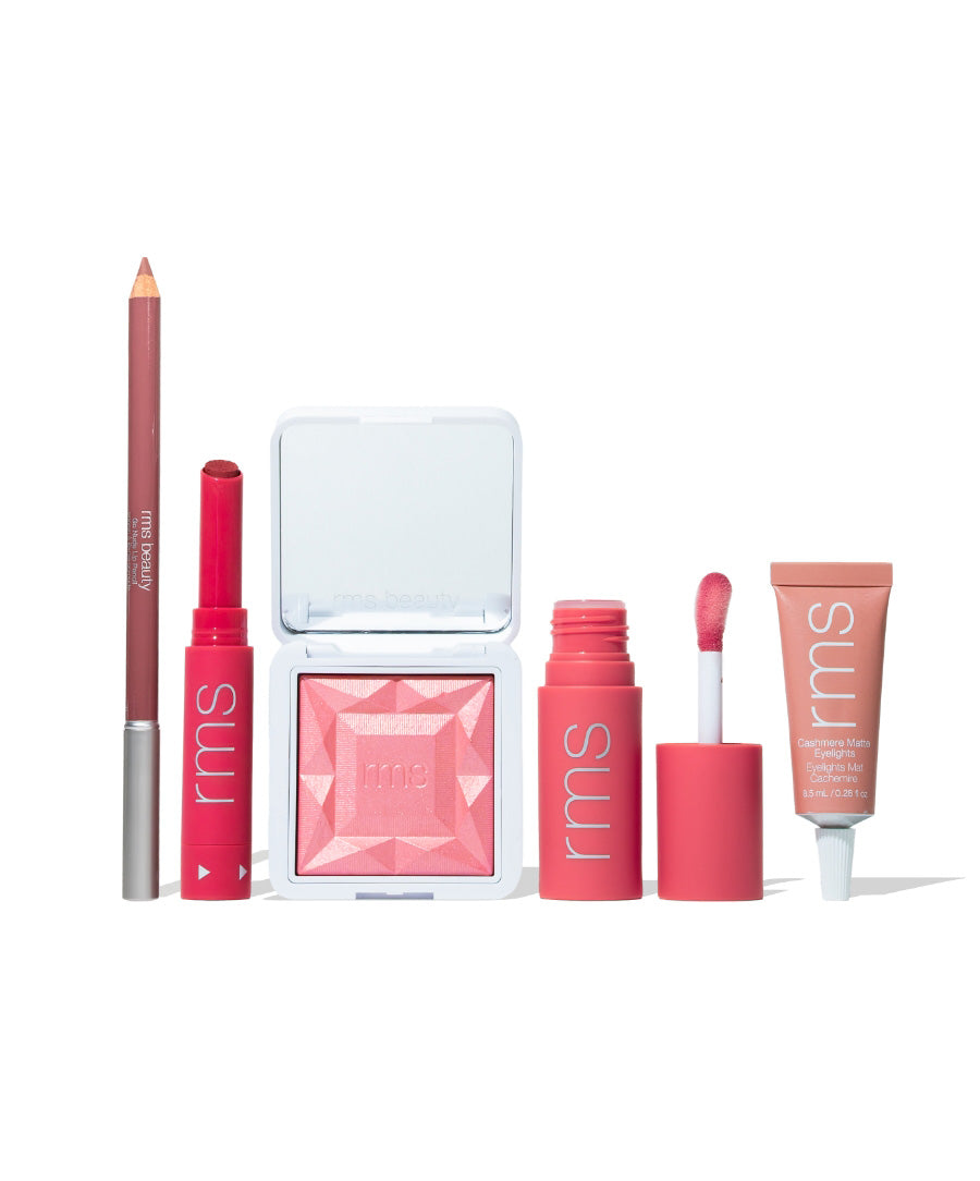 A set of pink-toned makeup products including a lip liner, two lip colors, a blush compact, and a cream product tube, labeled as Color Capsule: The Rosé Edit by RMS Beauty, featuring clean beauty and natural ingredients.