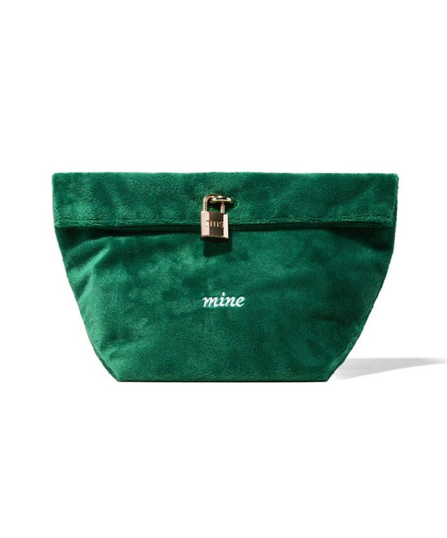 The Emerald Luxe Pouch in rich green velvet with a gold-tone lock detail and white embroidered "mine" text, perfect for stylish and secure storage.