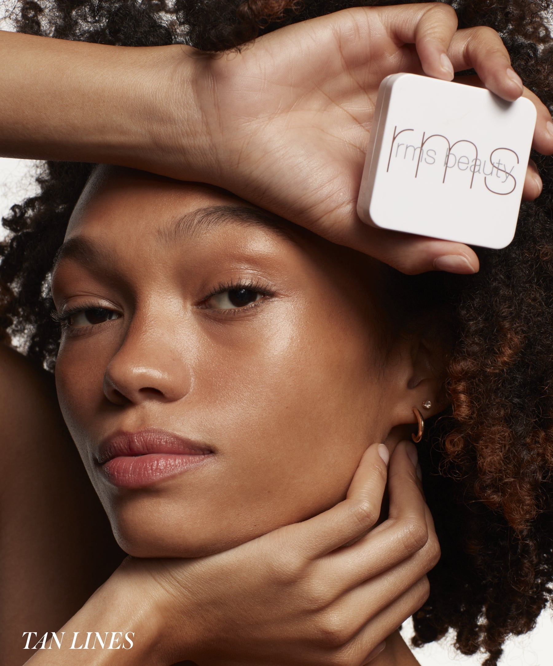 Close-up of a woman with natural glowing skin holding a compact makeup case labeled ReDimension Hydra Bronzer, showcasing a radiant and sun-kissed complexion with clean beauty appeal.