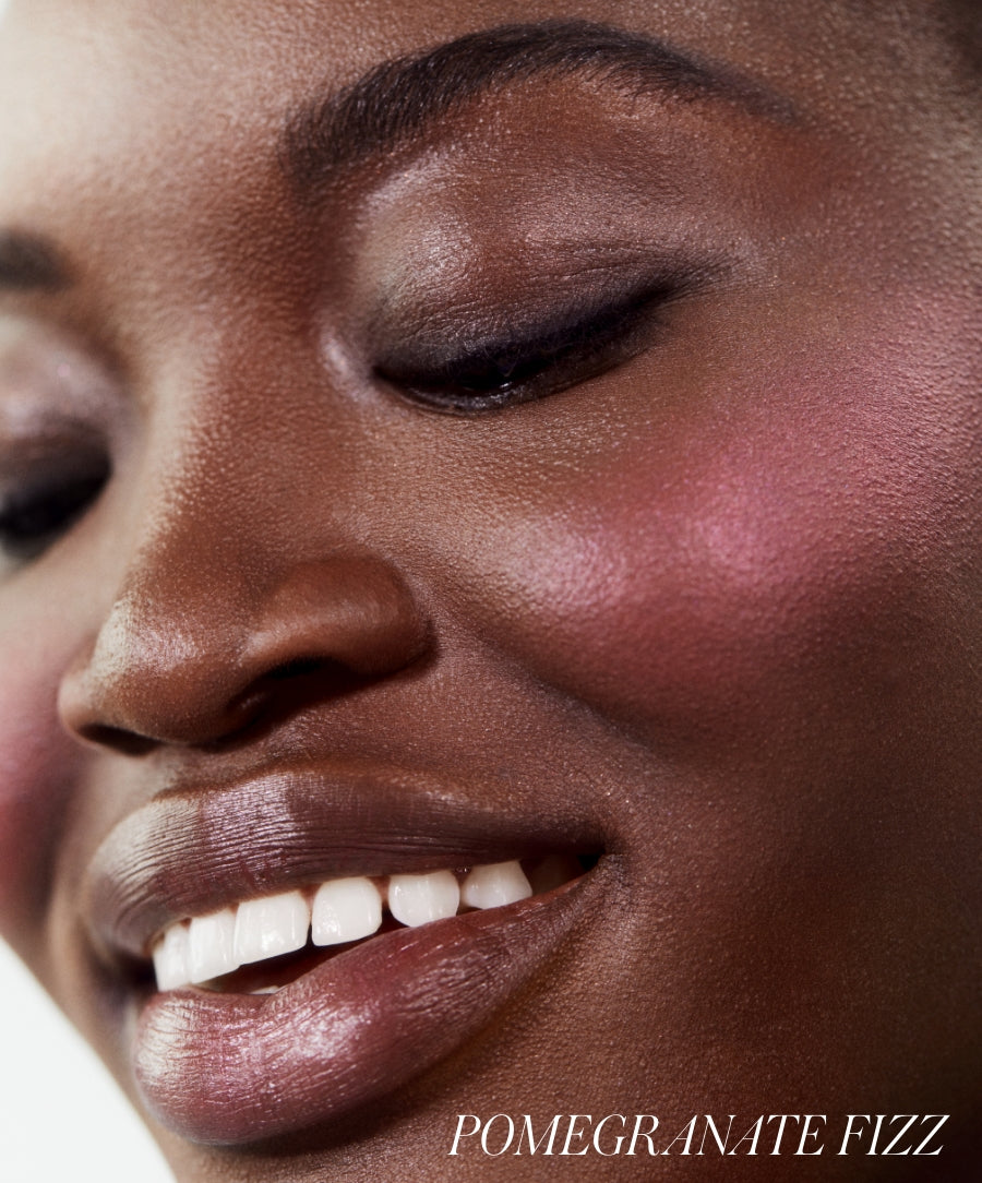 Close-up of a smiling woman with smooth skin wearing the ReDimension Hydra Powder Blush in a vibrant pink shade, highlighting natural ingredients and clean beauty benefits.
