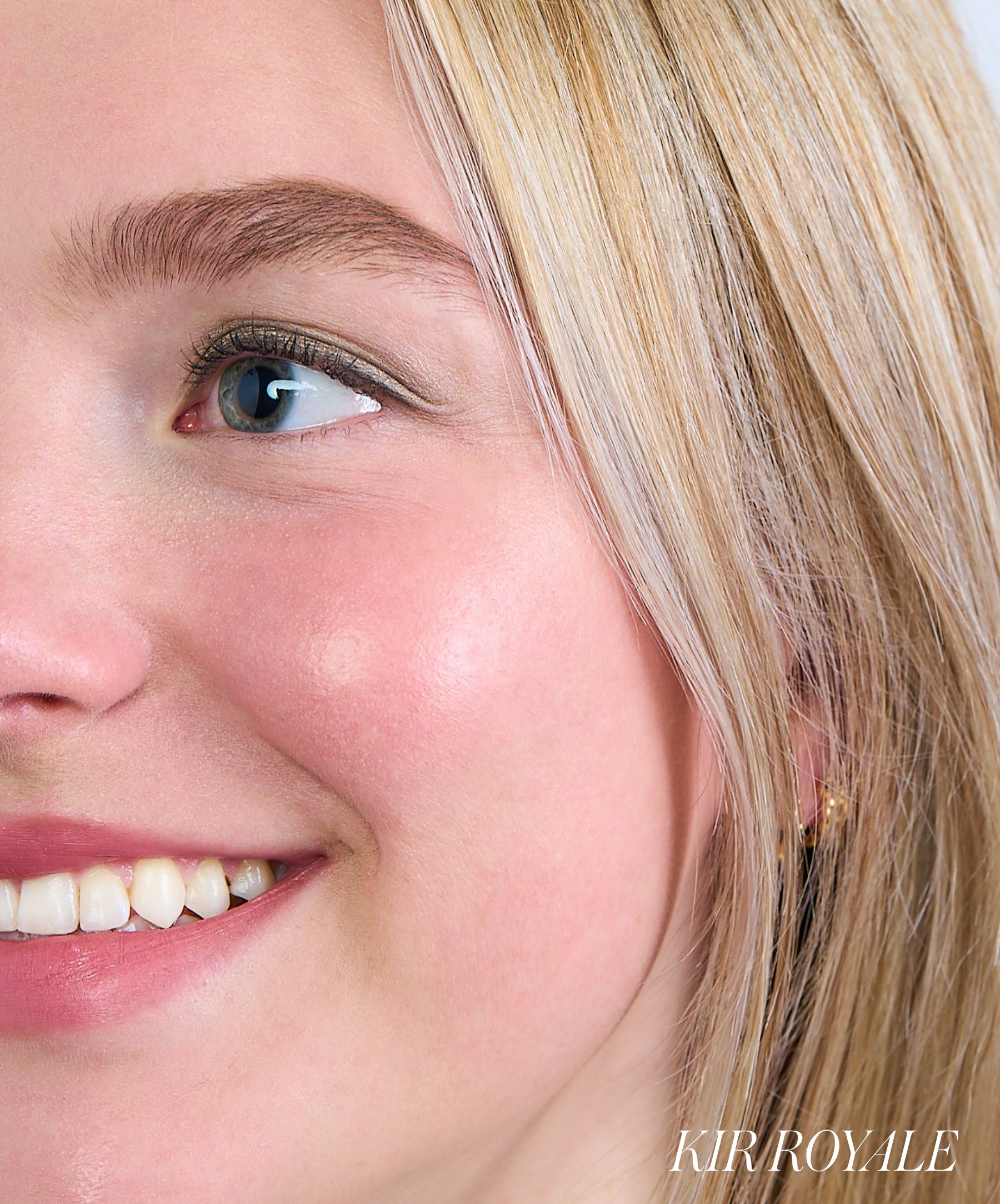 Close-up of a smiling woman with blonde hair showcasing a natural rosy glow on her cheek using ReDimension Hydra Powder Blush for a fresh, clean beauty look.