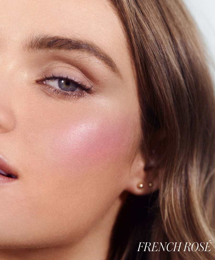 Close-up of a woman’s face featuring soft pink blush on her cheek, showcasing the natural, radiant finish of ReDimension Hydra Powder Blush in French Rosé by RMS Beauty.