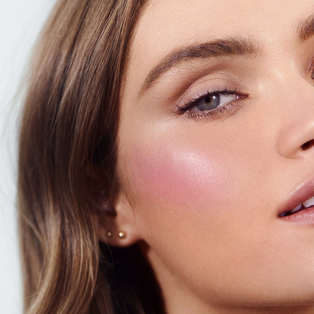 Close-up of a woman’s face showcasing soft pink cheeks enhanced with ReDimension Hydra Powder Blush, highlighting the natural, clean beauty look with a subtle radiant finish.