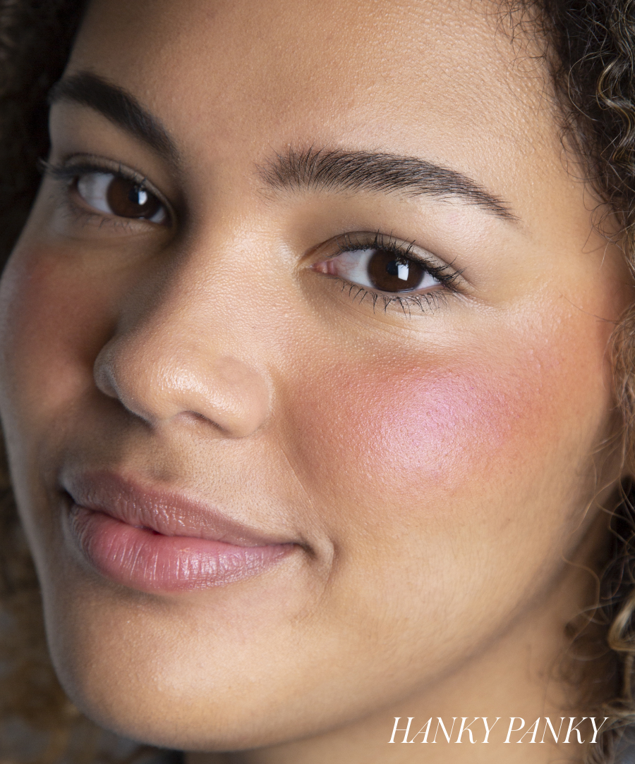 Close-up of a smiling woman wearing subtle pink blush on her cheek showcasing the natural, radiant finish of ReDimension Hydra Powder Blush from RMS Beauty, highlighting clean beauty and skincare infused makeup.