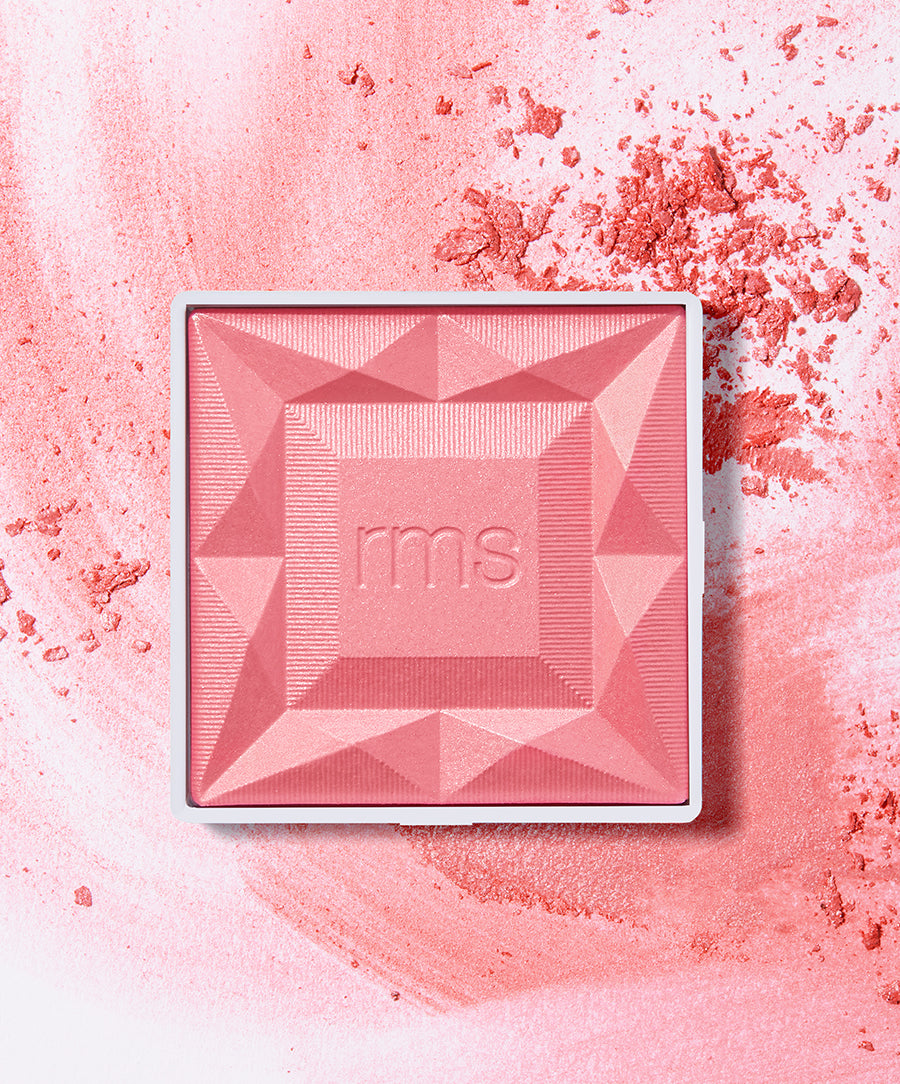 ReDimension Hydra Powder Blush in a soft pink shade with a geometric embossed design, surrounded by loose blush powder, showcasing clean beauty and natural ingredients.